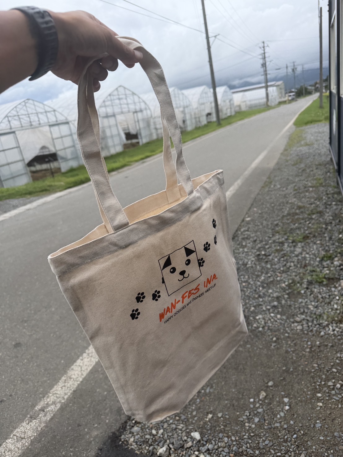 犬のマークと足あと、オレンジ色の文字をあしらったナチュラルカラーのトートバッグ。